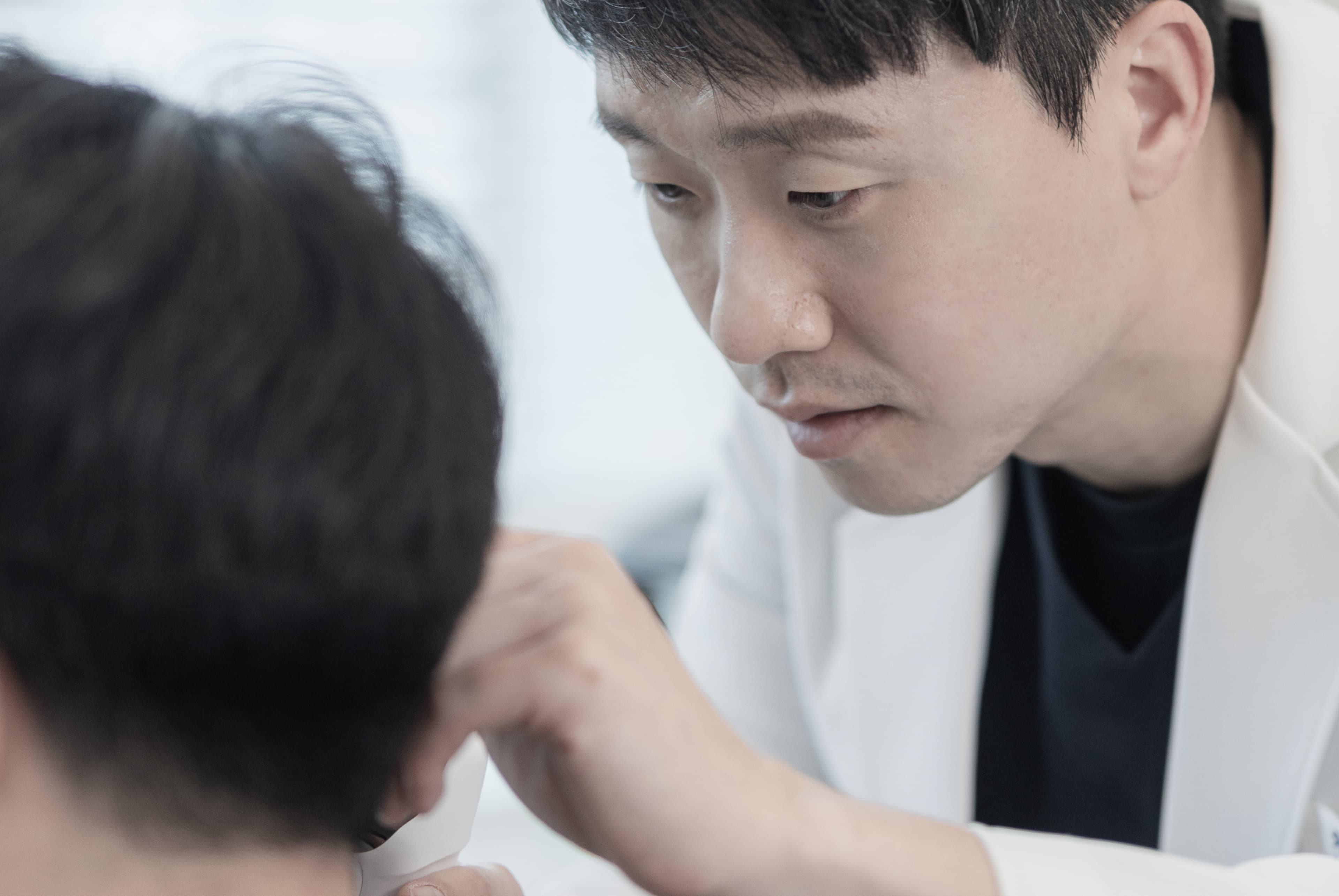 안양프라임메디의원 가정의학과 전문의 문다운 원장이 환자의 목과 어깨 부위를 손으로 짚어가며 세심하게 진찰하는 모습. 신뢰감 있는 진료 태도와 밝은 진료 환경이 함께 담겨 있다.