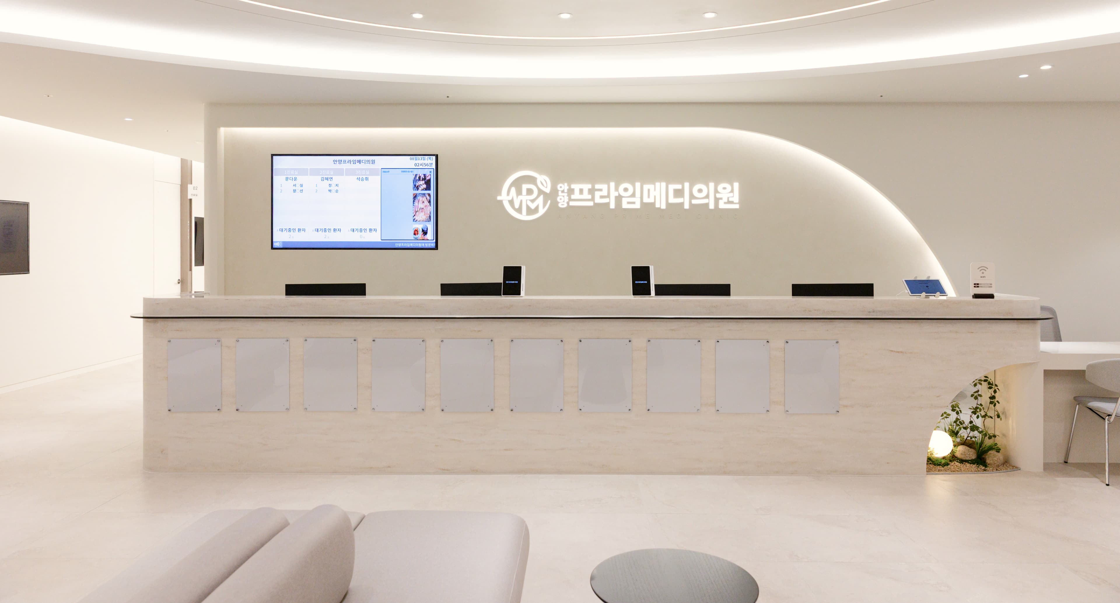 안양프라임메디의원 접수 데스크 전경. 병원 로고가 부착된 안내 모니터와 정돈된 데스크가 배치되어 있어, 방문 시 첫인상을 담당하는 접수 공간을 보여준다.